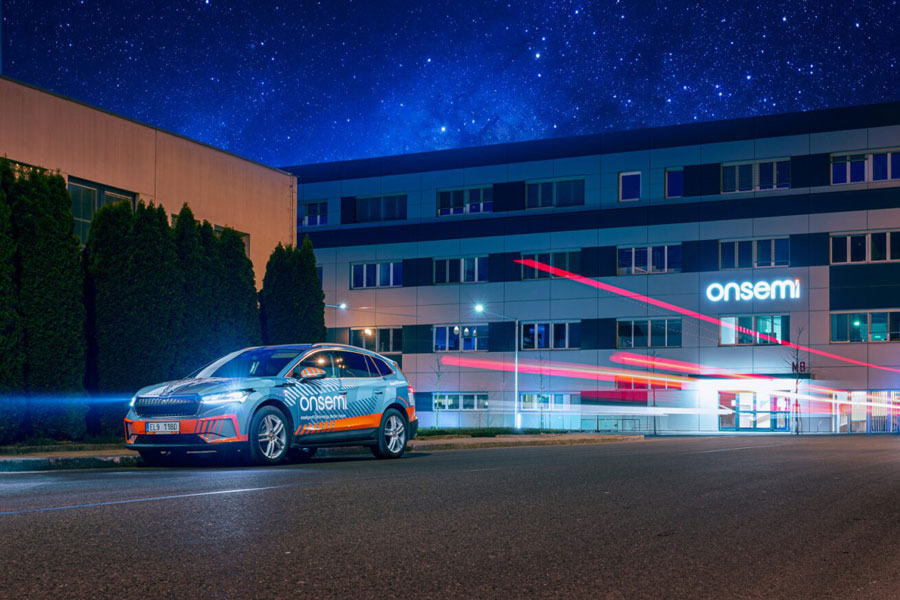An electric car with onsemi graphics driving quickly past a branch in Roznov.